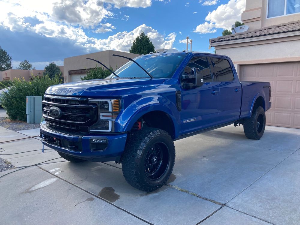 A blue ford truck is parked in front of a garage.