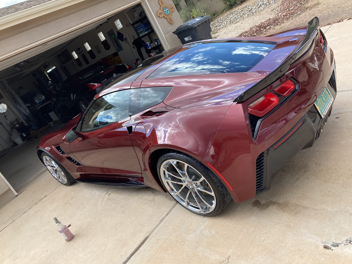 A red sports car is parked in front of a garage.