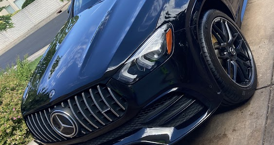 A blue mercedes benz is parked on the side of the road.