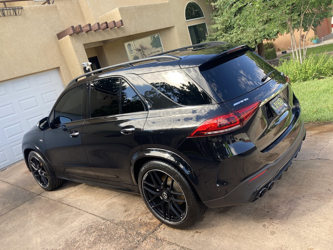 A black suv is parked in front of a garage door.