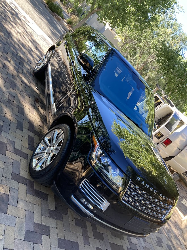 A black range rover is parked on a brick driveway.