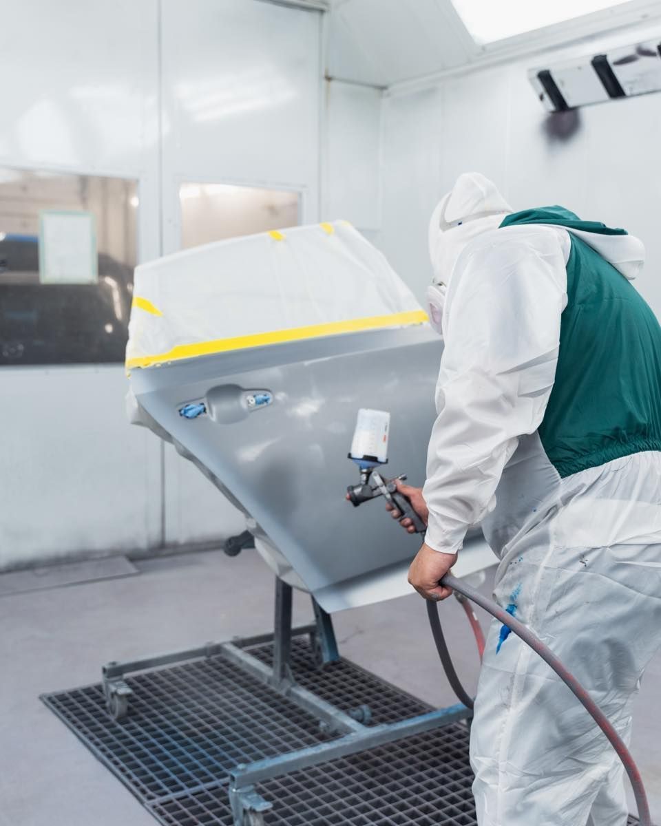 Technician Painting White Vehicle Hood In Spray Booth | D&V Autobody Overland