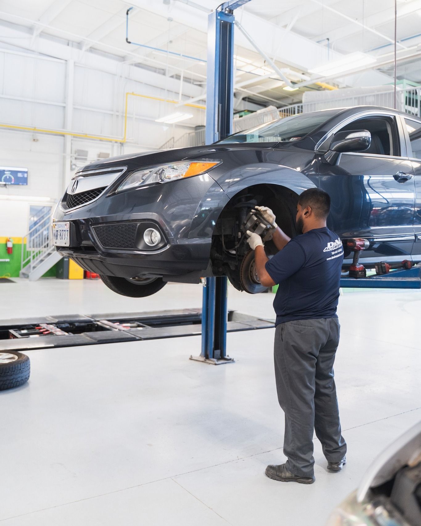 Technician Inspecting Black Car On Lift | D&V Autobody Overland