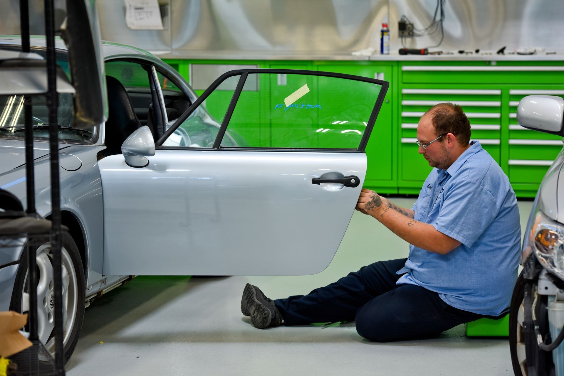 Technician Painting White Car Door In Shop | D&V Autobody