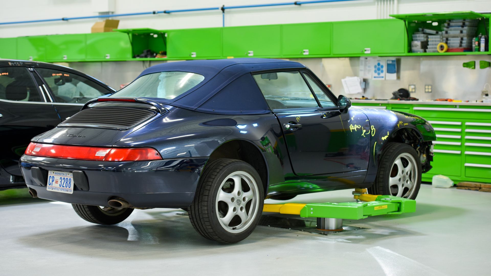 Black Porsche On Shop Floor Near Workbench | D&V Autobody