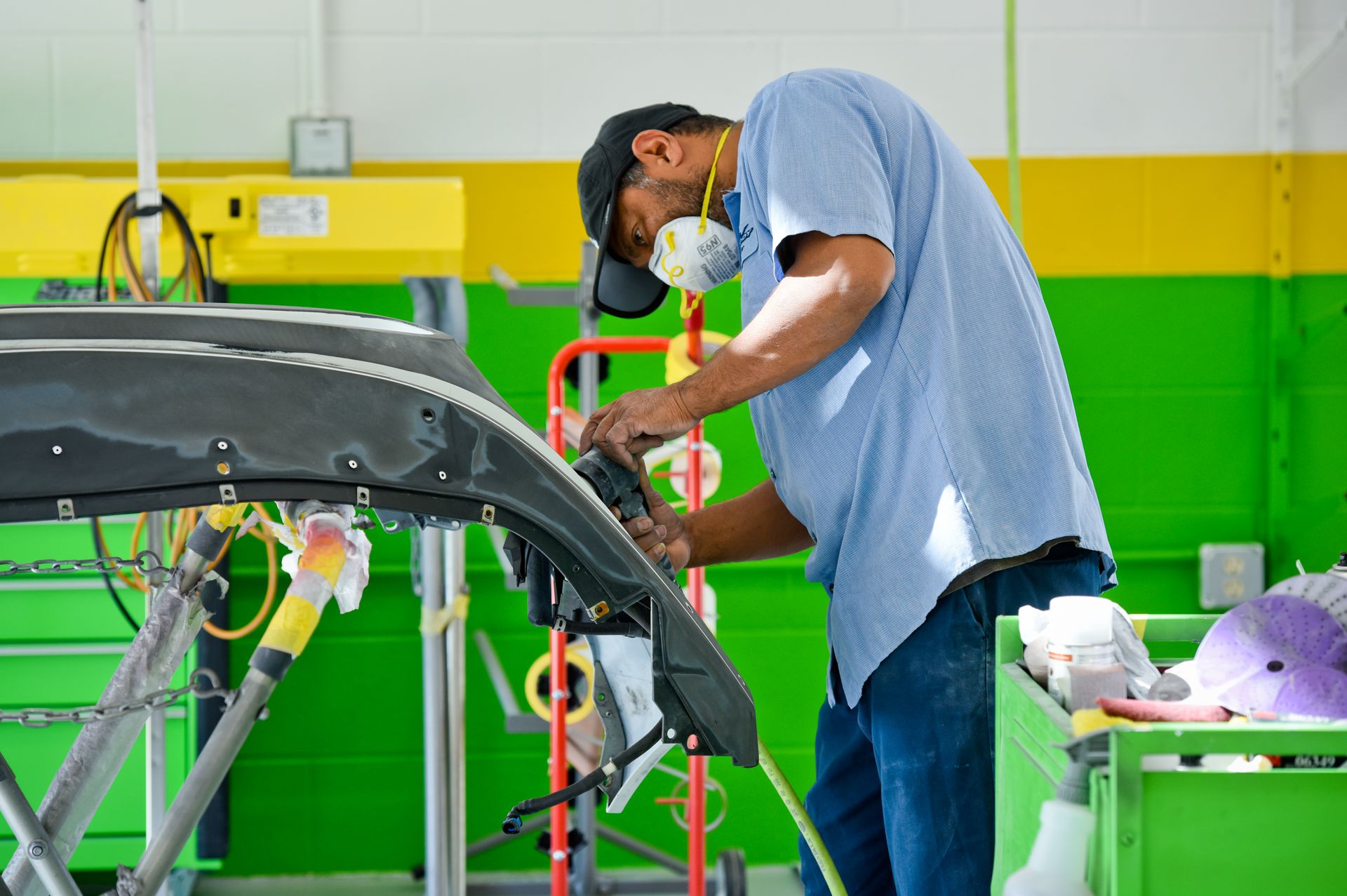 Technician Sanding Car Bumper On Work Stand | D&V Autobody