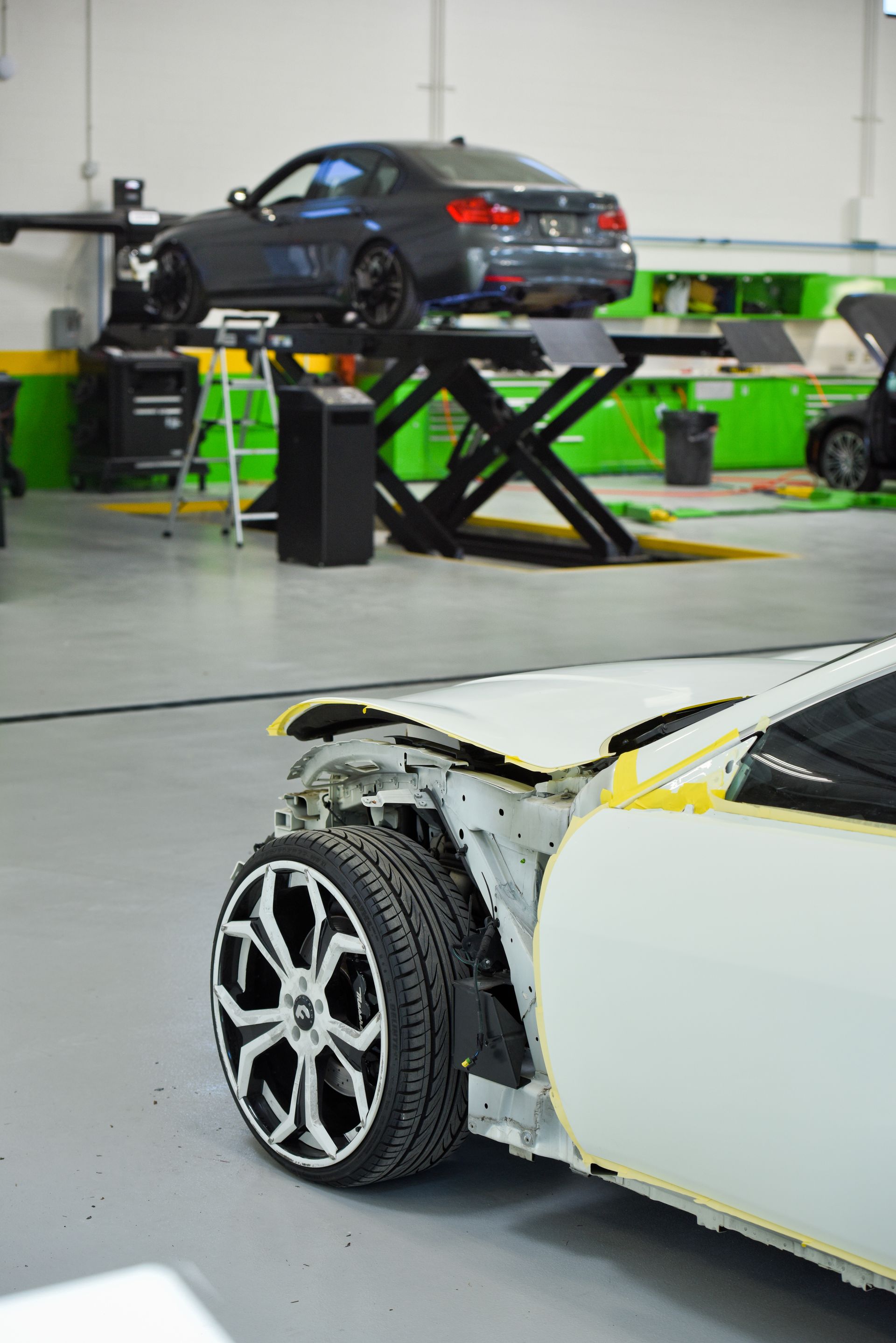 White Vehicle Lifted Inside Repair Facility | D&V Autobody