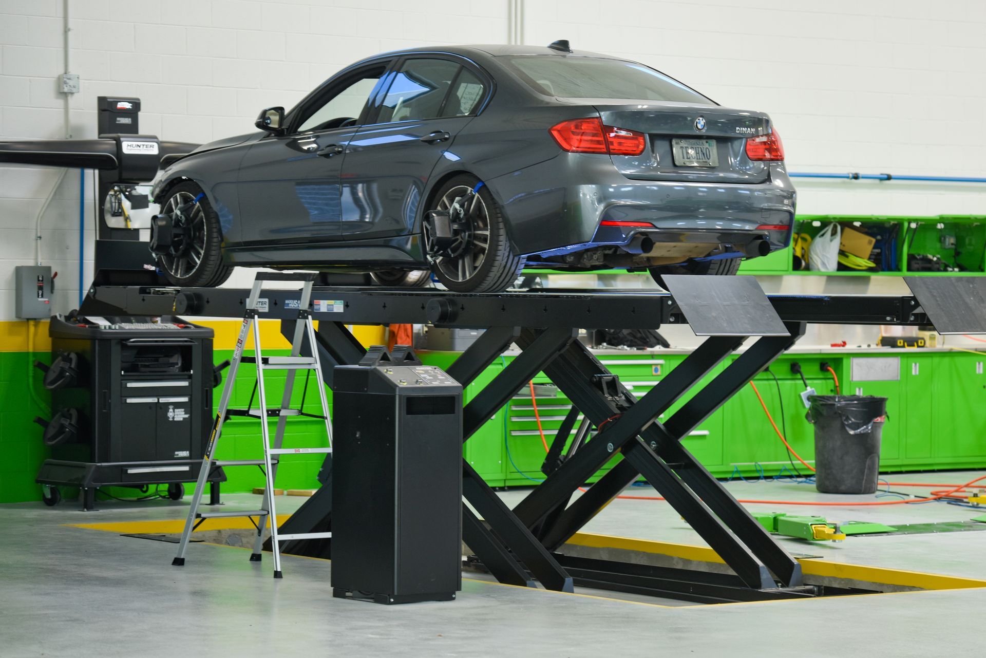 Silver Car Lifted On Hydraulic Alignment Machine | D&V Autobody
