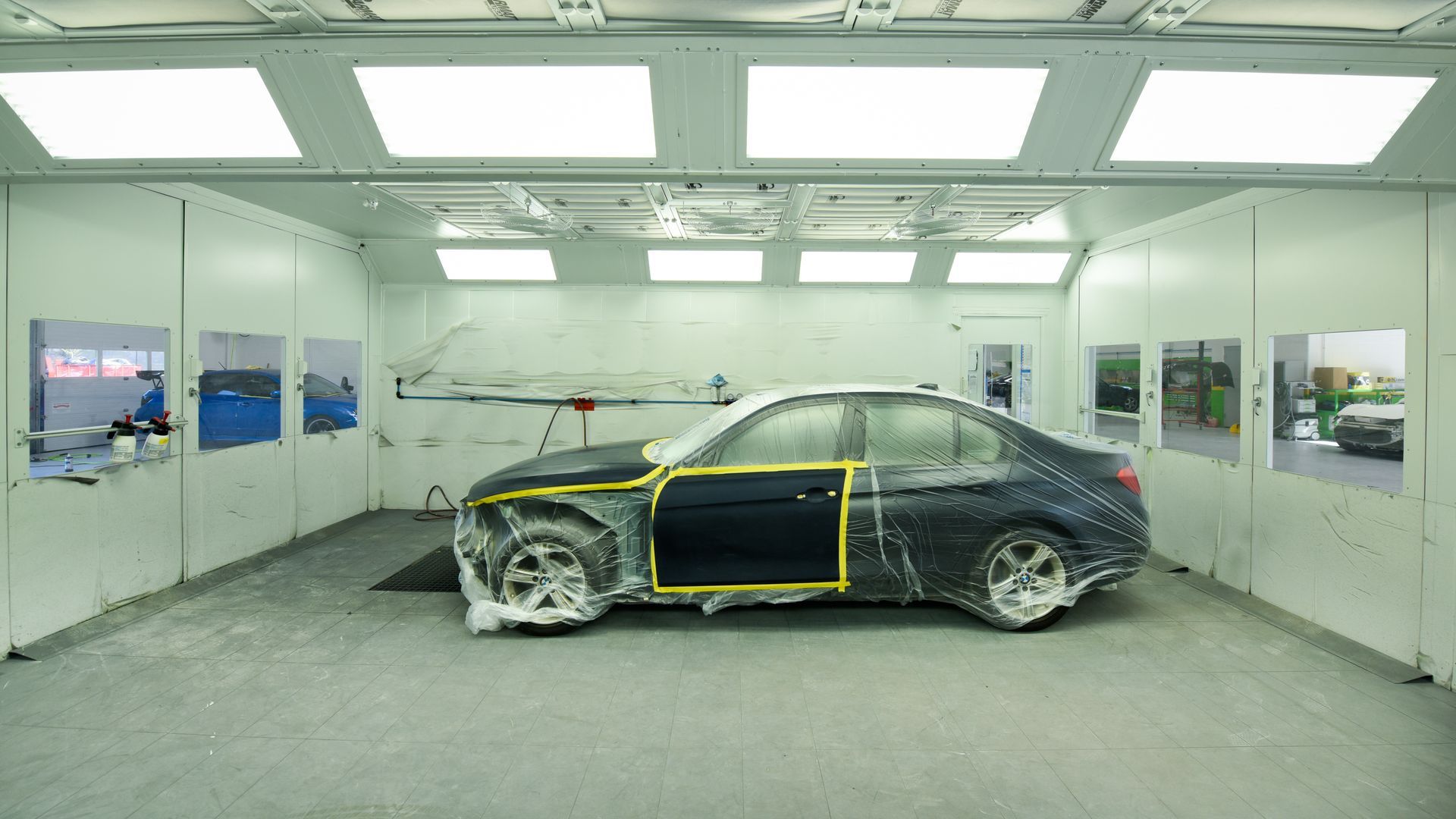 Black Car Inside Paint Booth With Yellow Tape | D&V Autobody