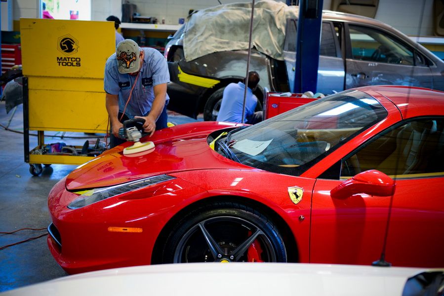 a man is polishing a red sports car in a garage