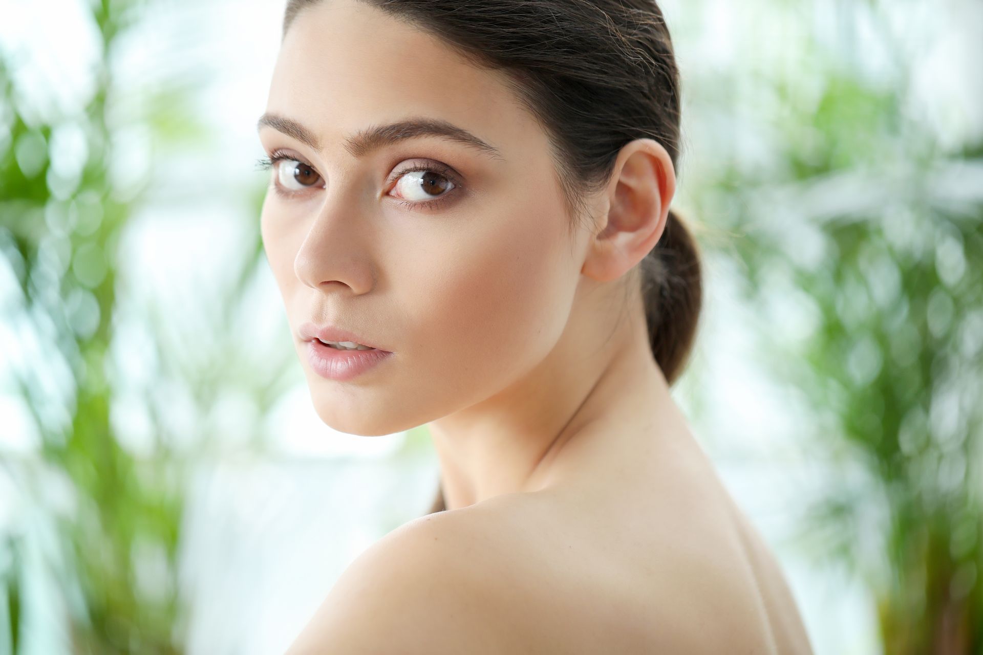 A woman with a ponytail is looking over her shoulder at the camera.