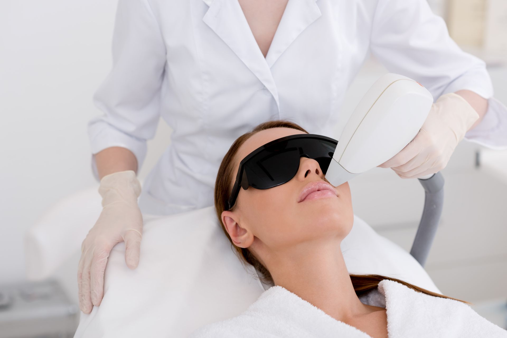 A woman is getting a laser hair removal treatment on her face.