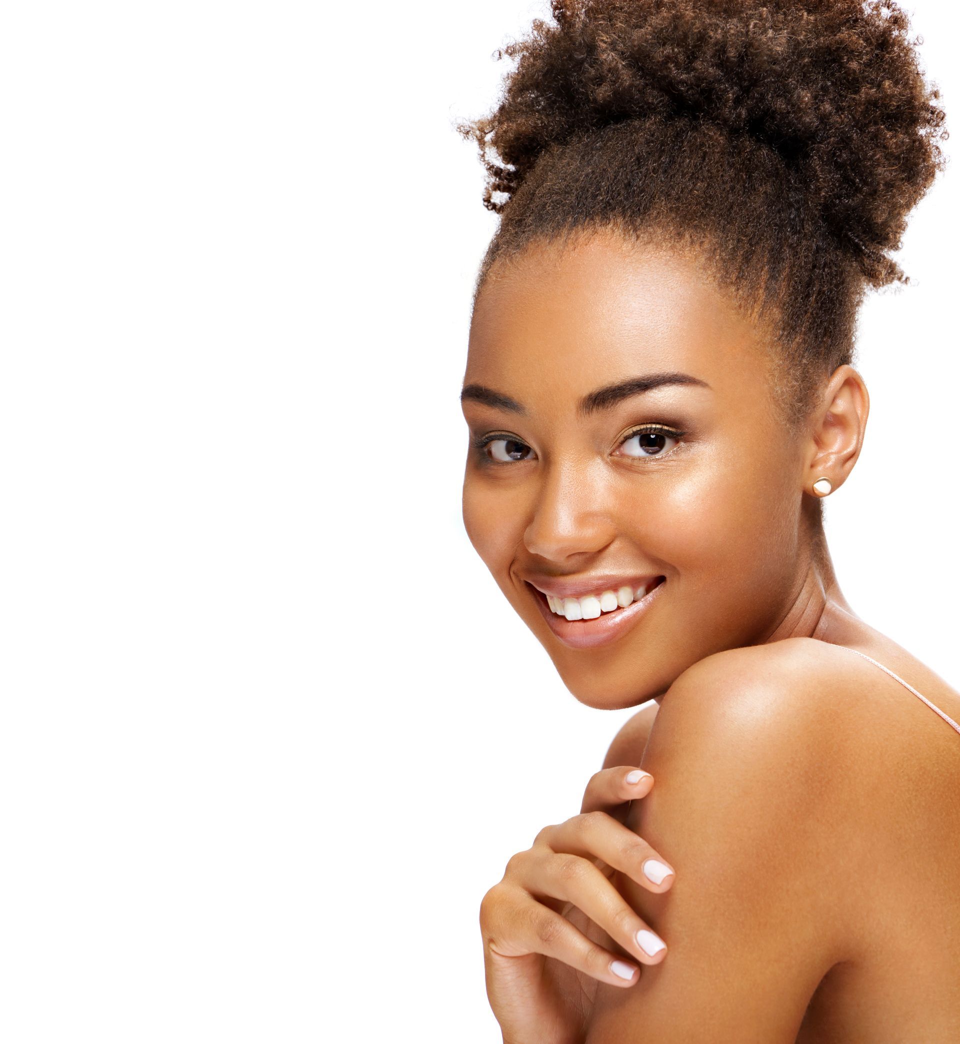 A woman with curly hair is smiling with her hand on her shoulder