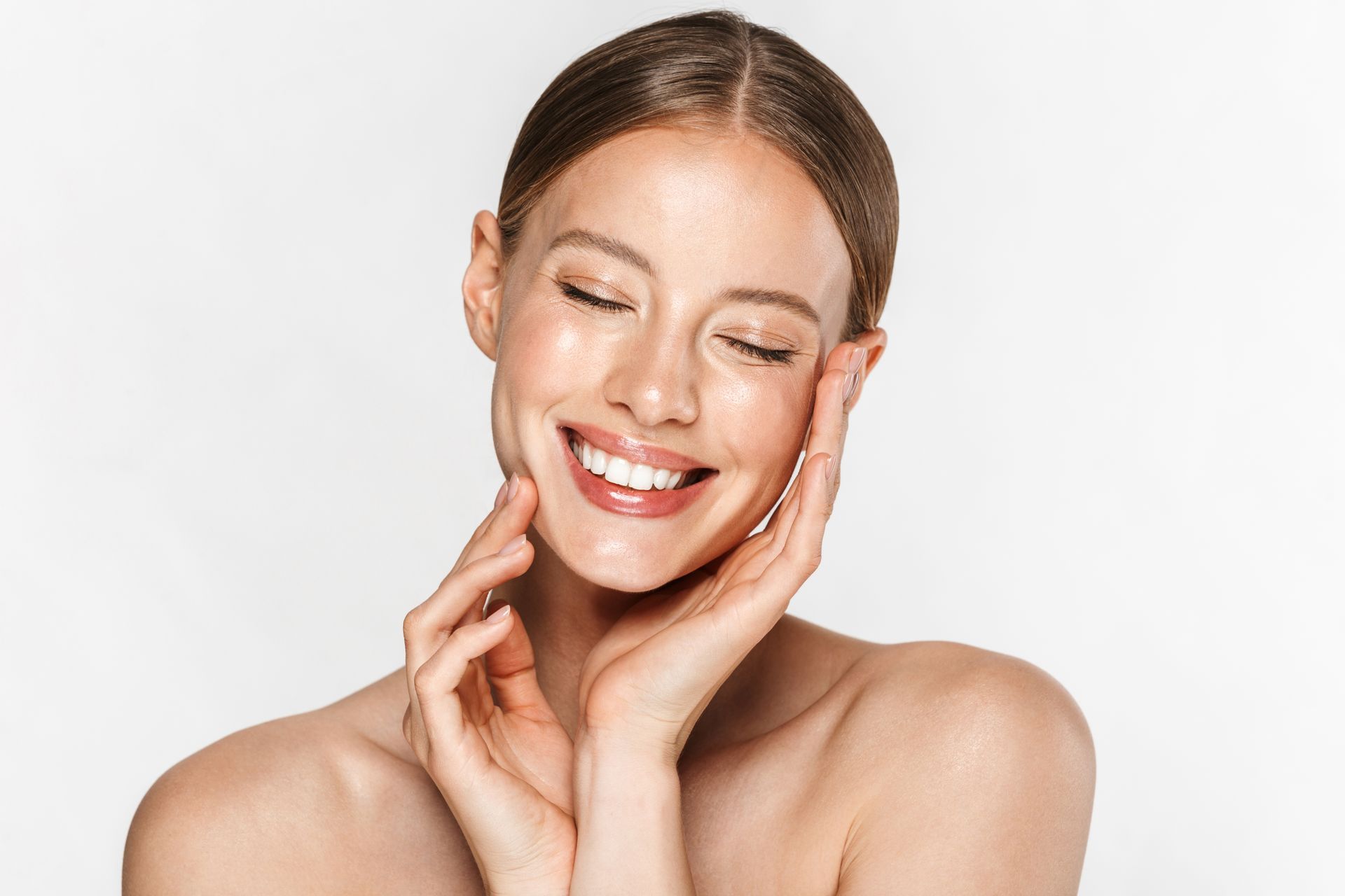 A woman is smiling and touching her face with her hands.