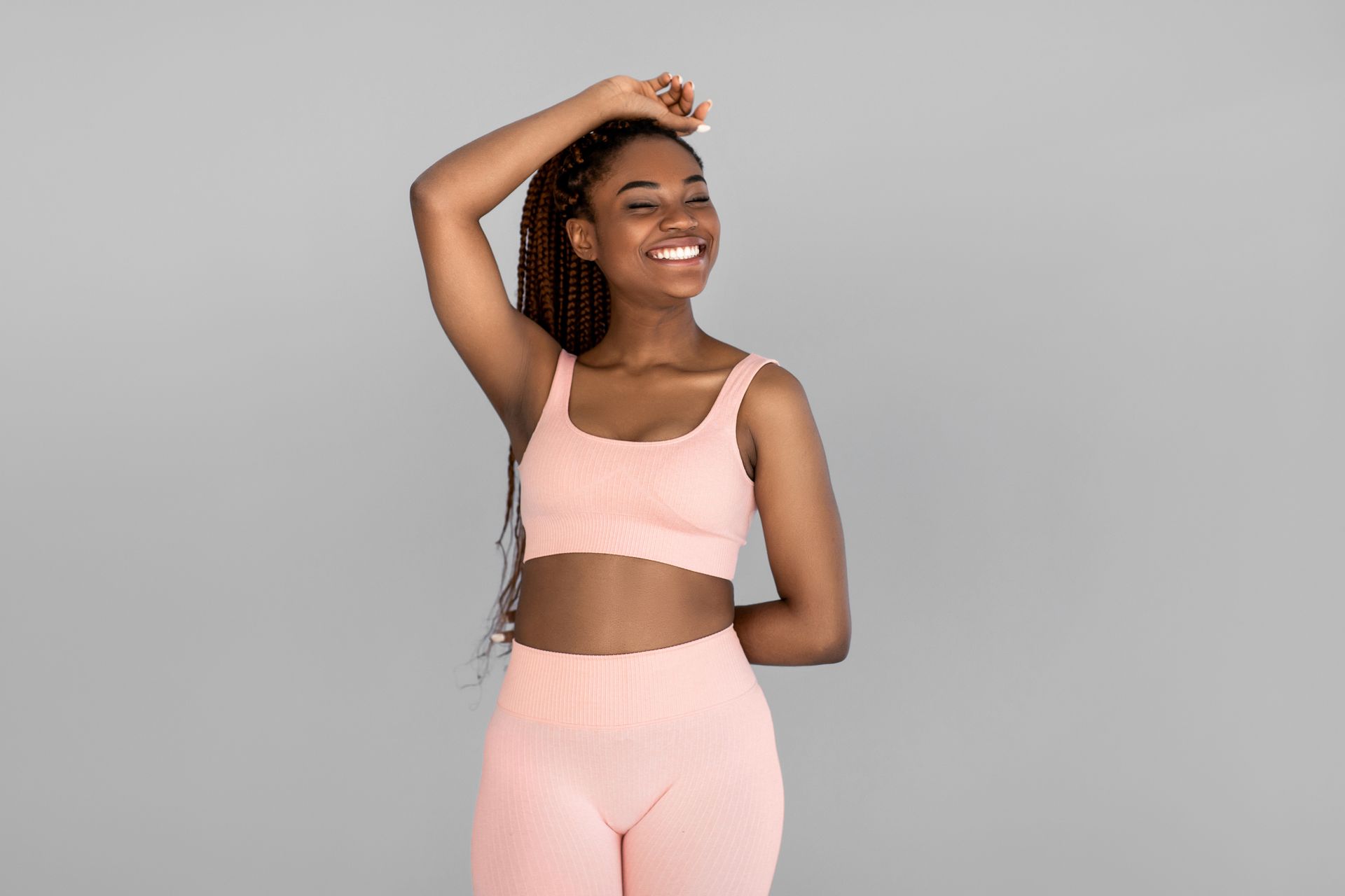 A woman in a pink sports bra and shorts is smiling.