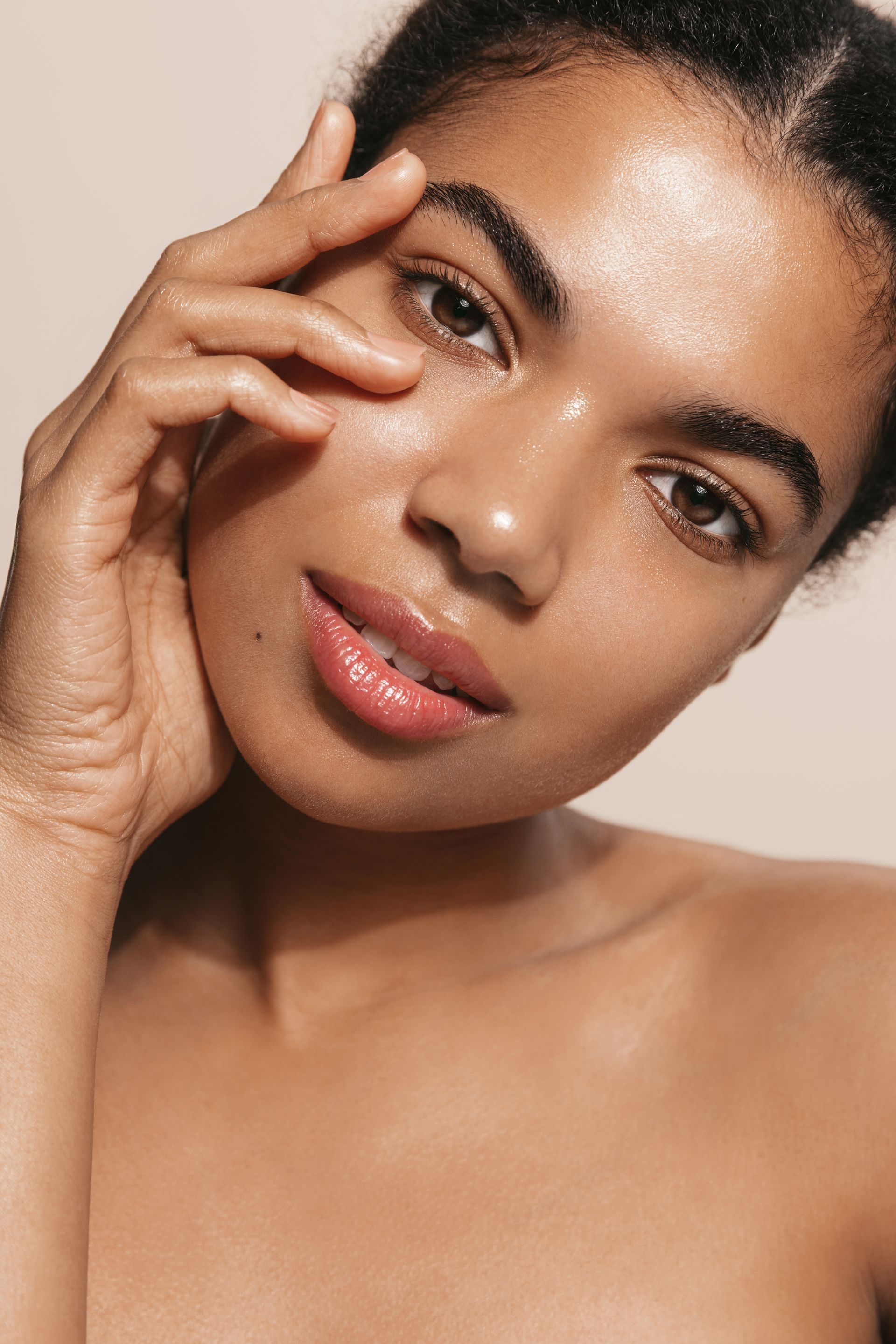 A woman is touching her face with her hand and looking at the camera.