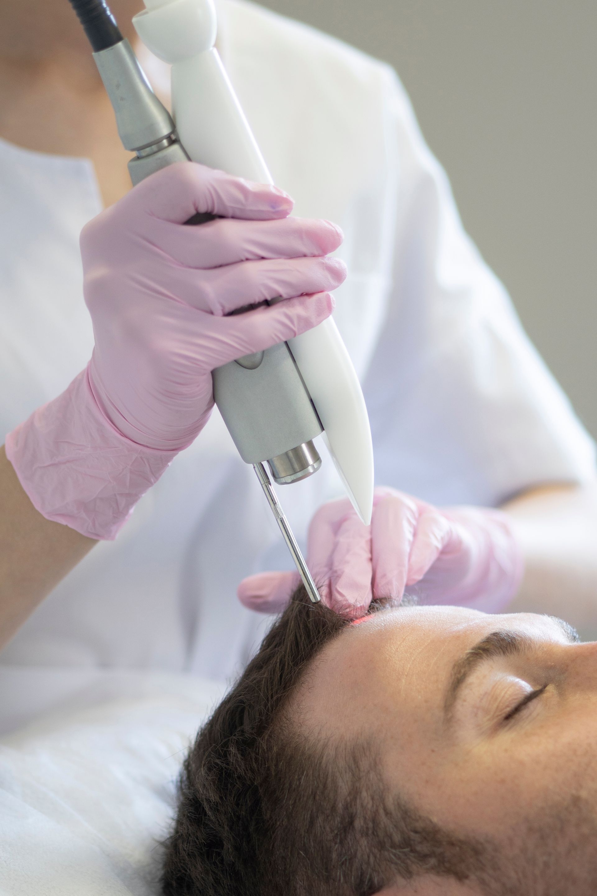 A man is getting a laser treatment on his forehead.