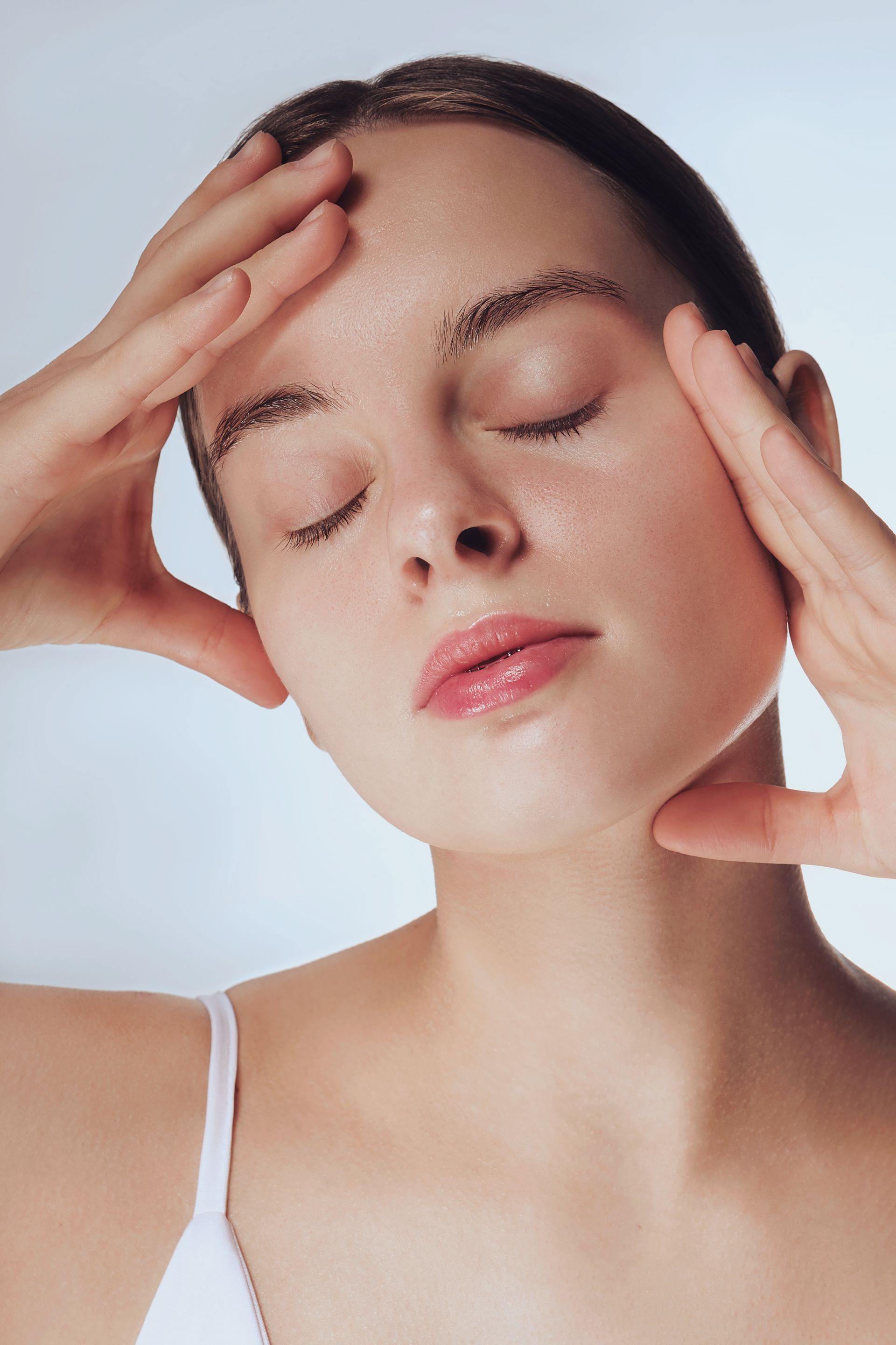 A woman is holding her head with her hands and her eyes closed