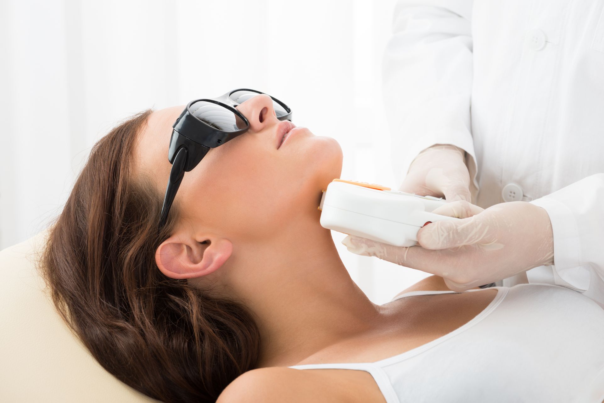 A woman is getting a laser hair removal treatment on her neck.