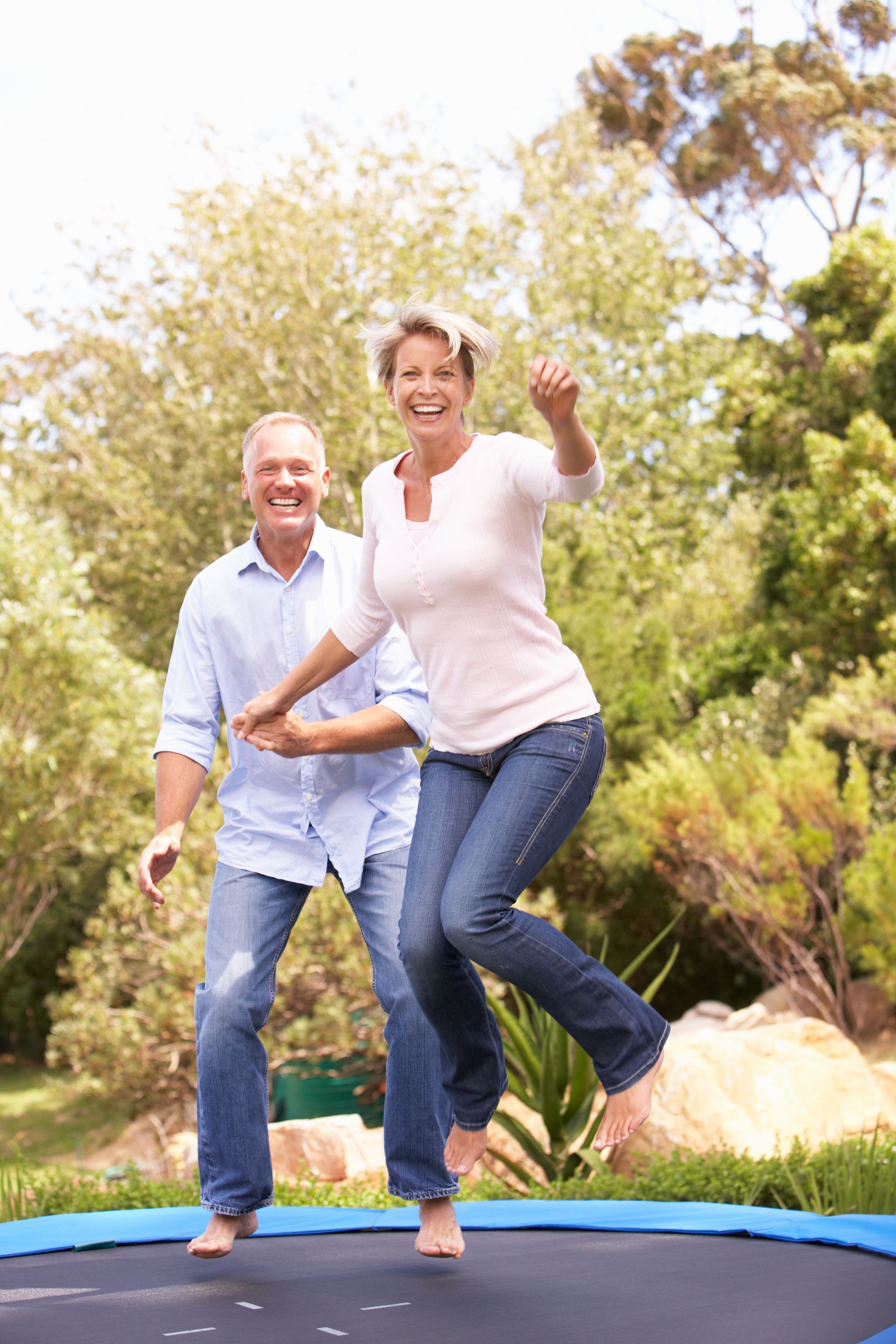 A man and a woman are jumping on a trampoline.