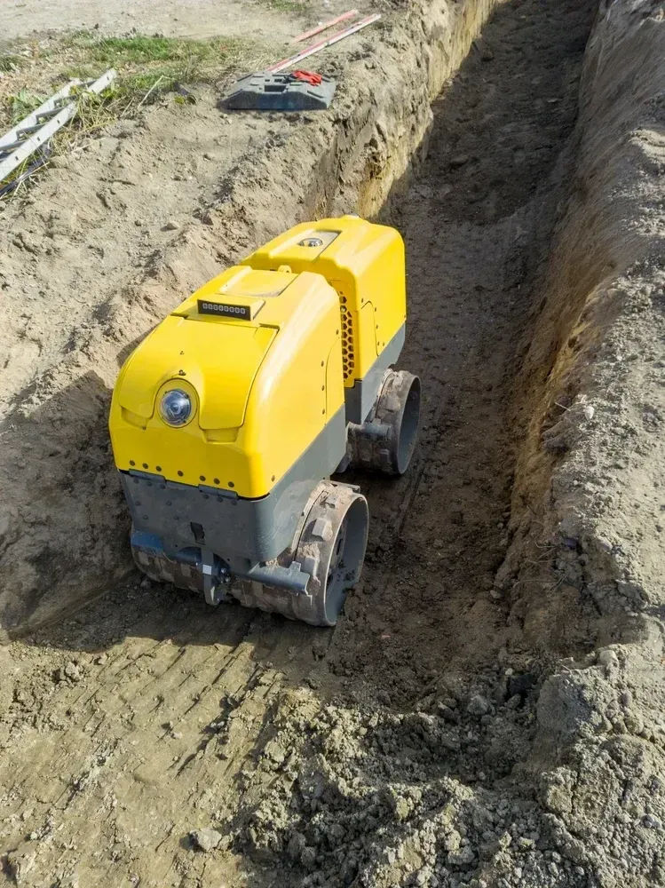 Yellow and gray trench compactor machine compacting soil in a construction trench. — Allquip Rentals Pty Ltd in Cooroy, QLD