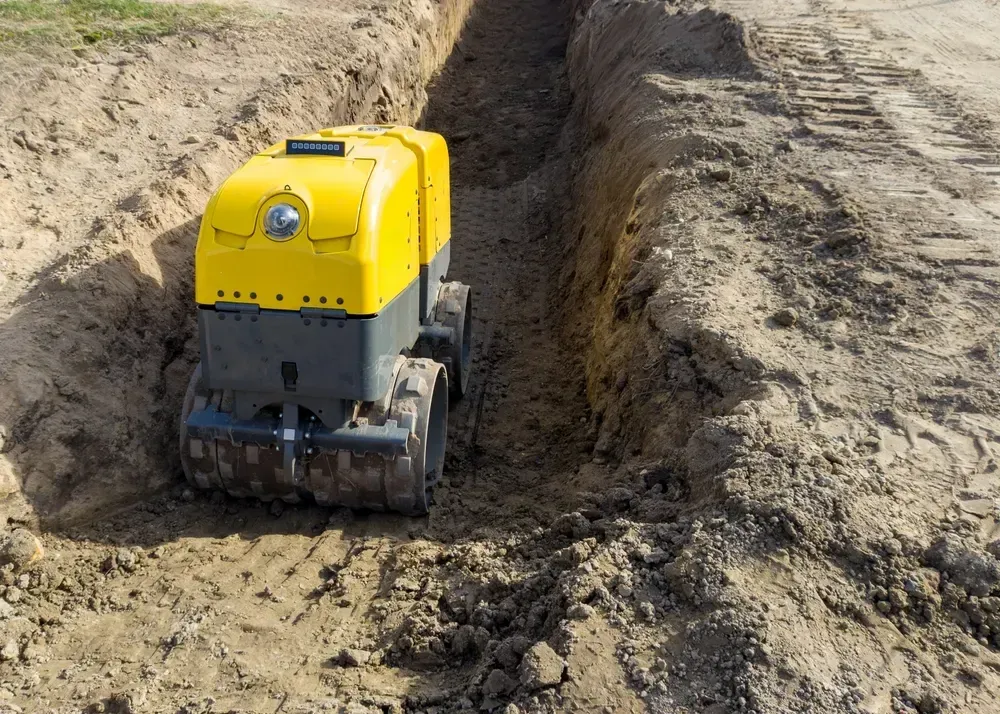 Yellow and gray trench compactor machine compacting soil in a newly dug trench. — Allquip Rentals Pty Ltd in Cooroy, QLD