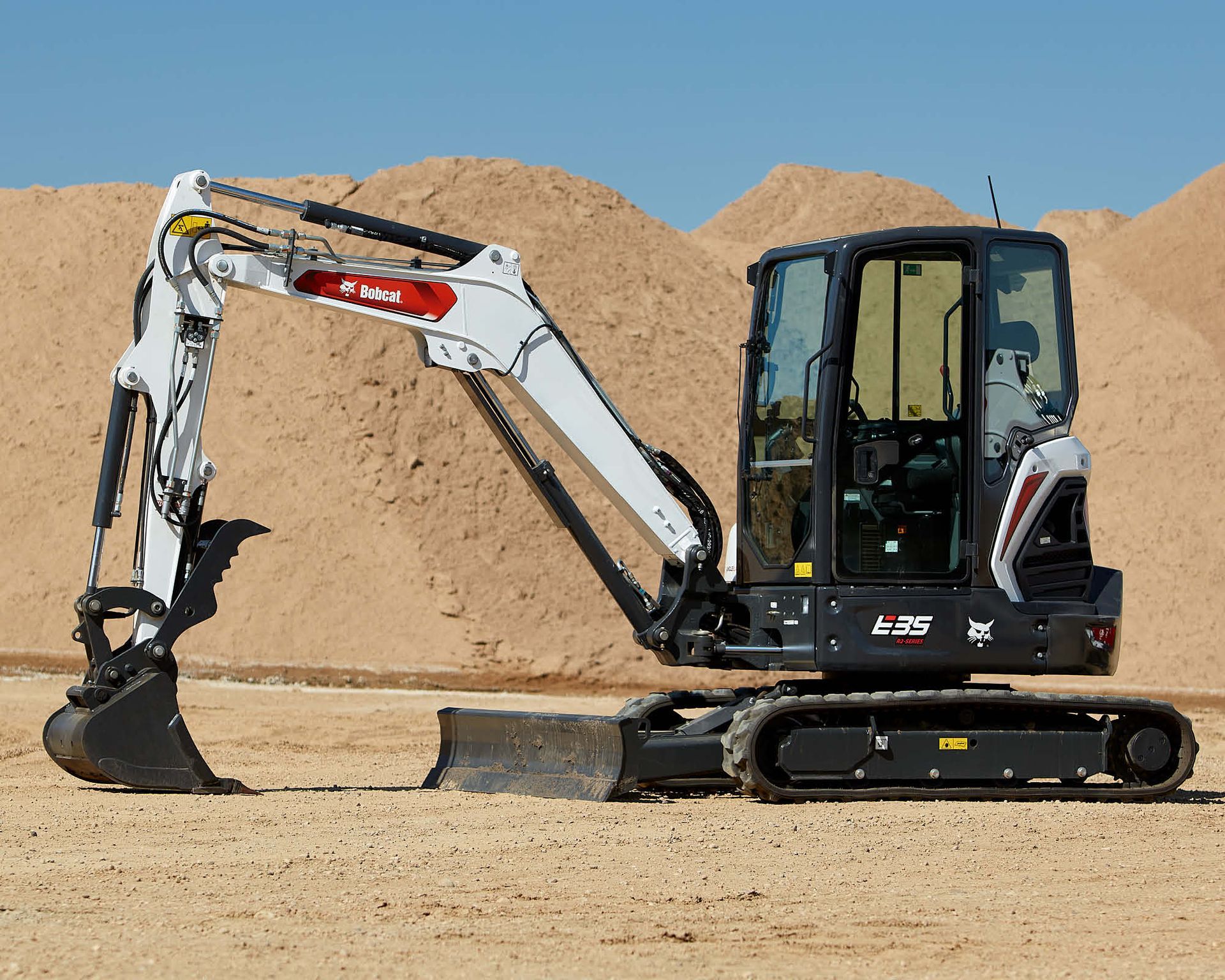 White Bobcat Excavator, Black Tracks, Digging in a Sandy Area — Allquip Rentals Pty Ltd in Cooroy, QLD