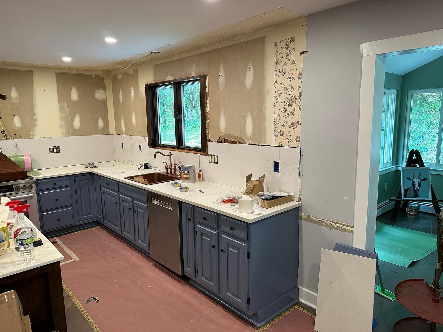 A kitchen with blue cabinets and white counter tops is being remodeled.