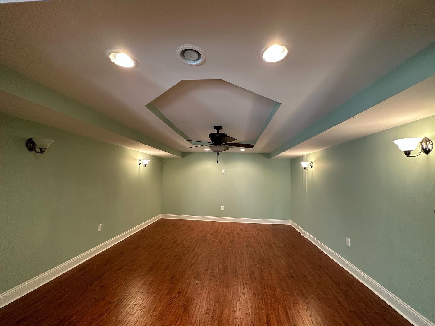 An empty room with wooden floors and a ceiling fan