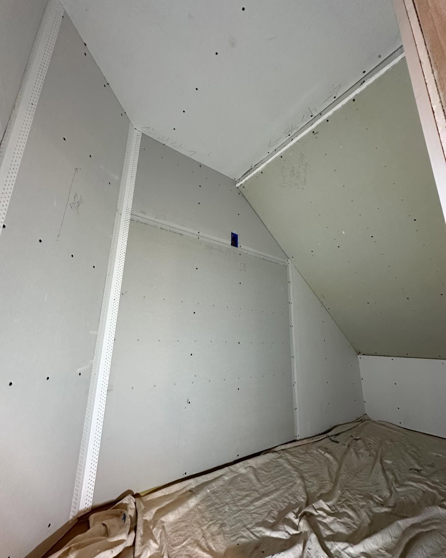 A room with a slanted ceiling and a blanket on the floor.