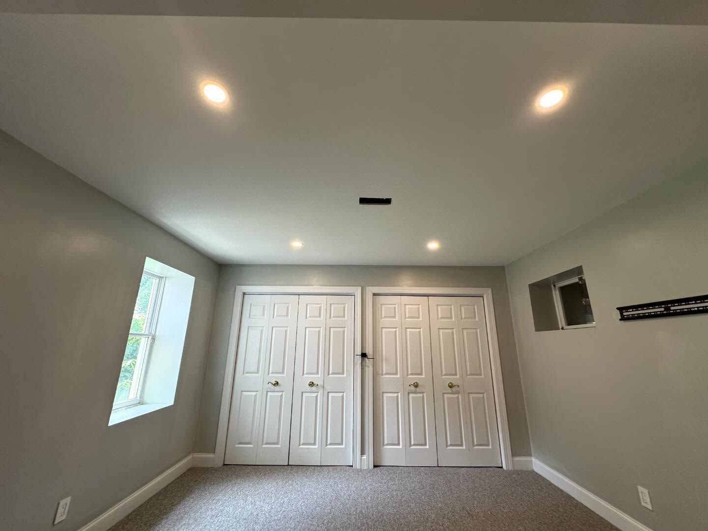 An empty room with two doors and a window.