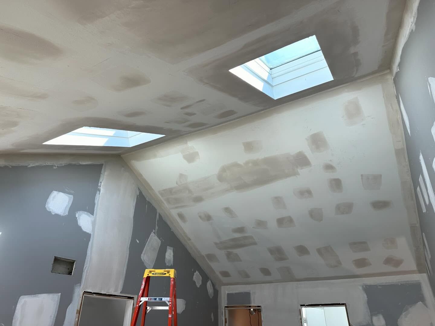 A room with a ladder and a skylight in the ceiling