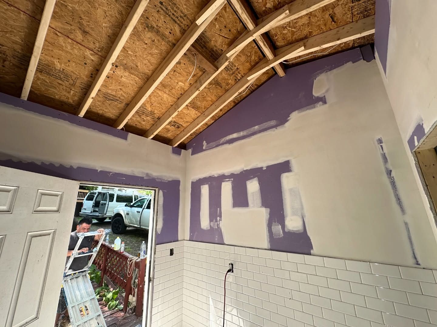 A room under construction with purple walls and white tiles.