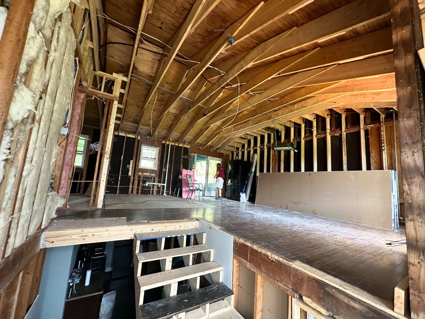 The inside of a house under construction with wooden beams and stairs.