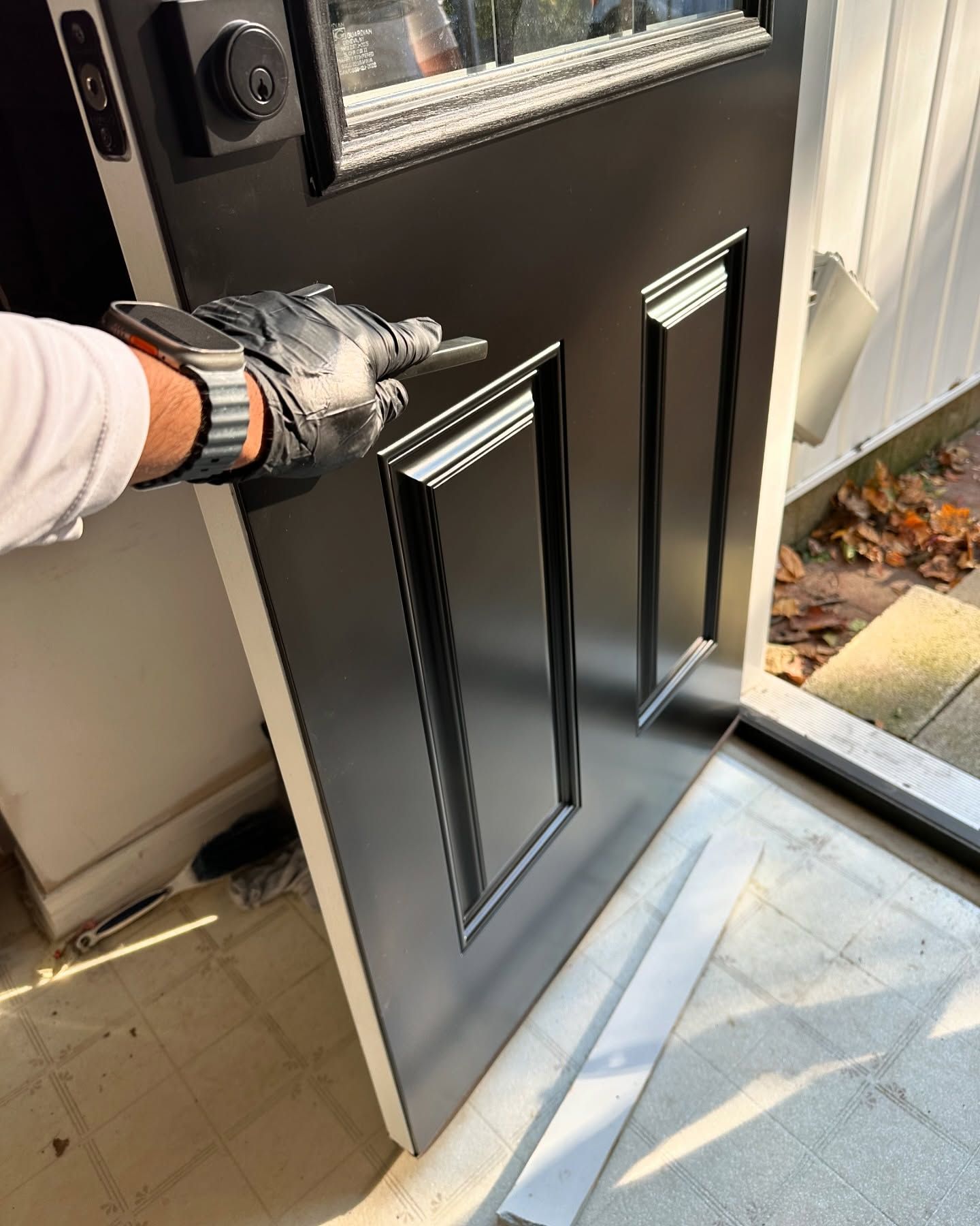 A person wearing gloves is opening a black door