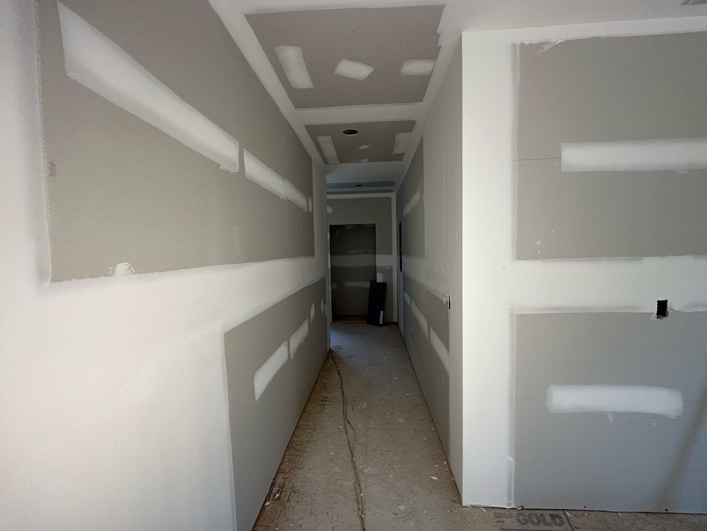 An empty hallway with drywall on the walls and ceiling