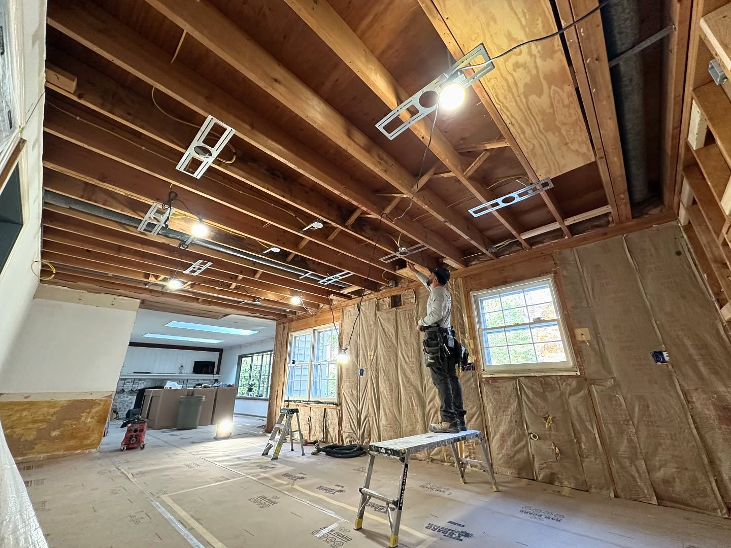 A man is standing on a ladder in a room under construction.