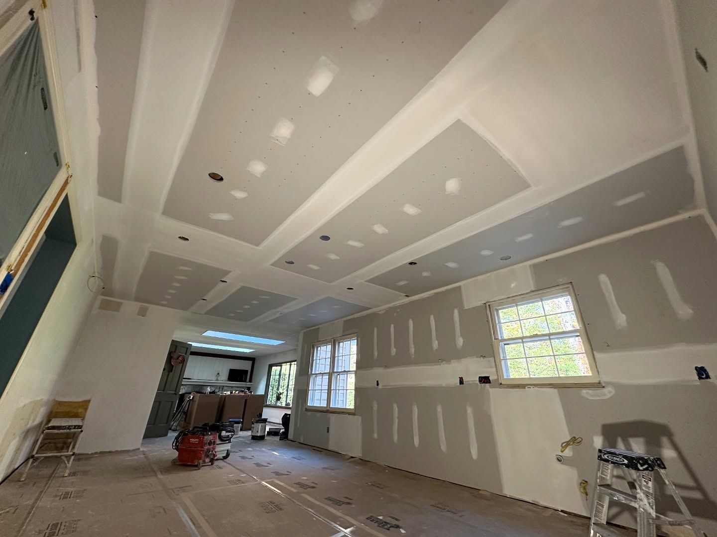 A room with a ladder and a vacuum cleaner in it is being remodeled.