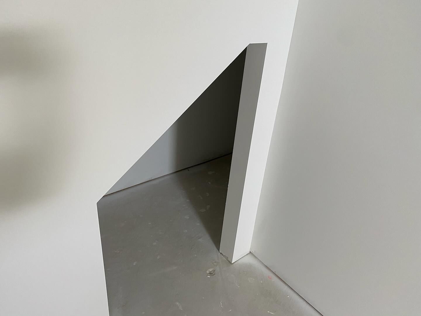 A corner of a white wall with a hole in it