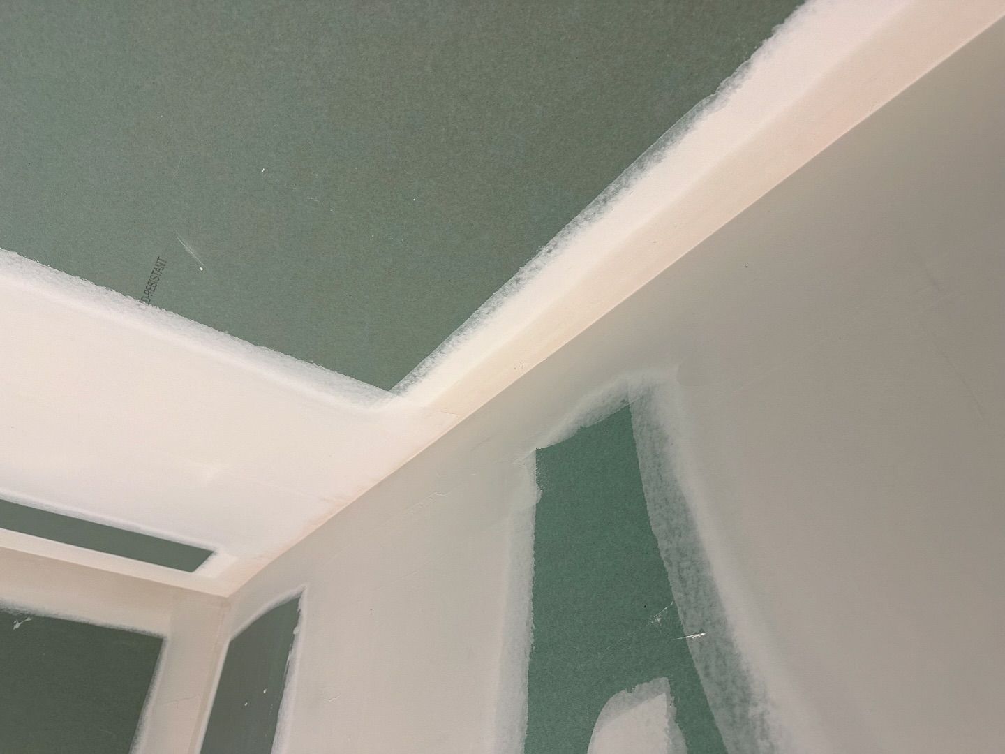 A room with a green wall and a white ceiling.