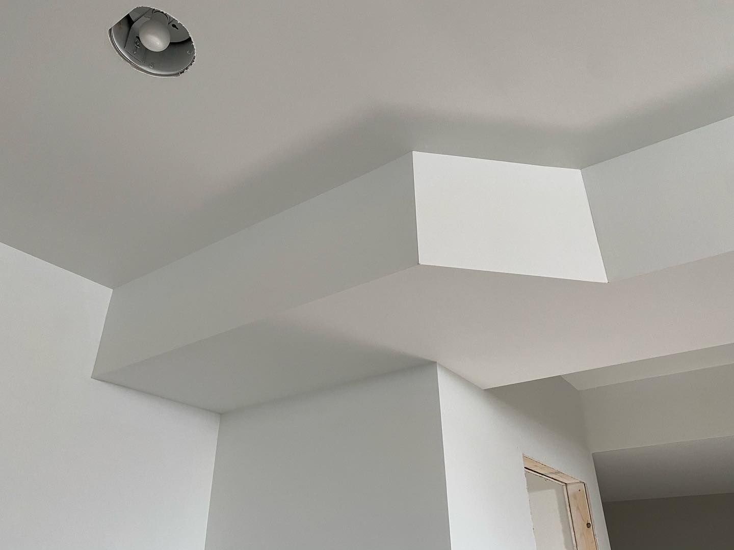 A ceiling with a square hole in it and a light on it.