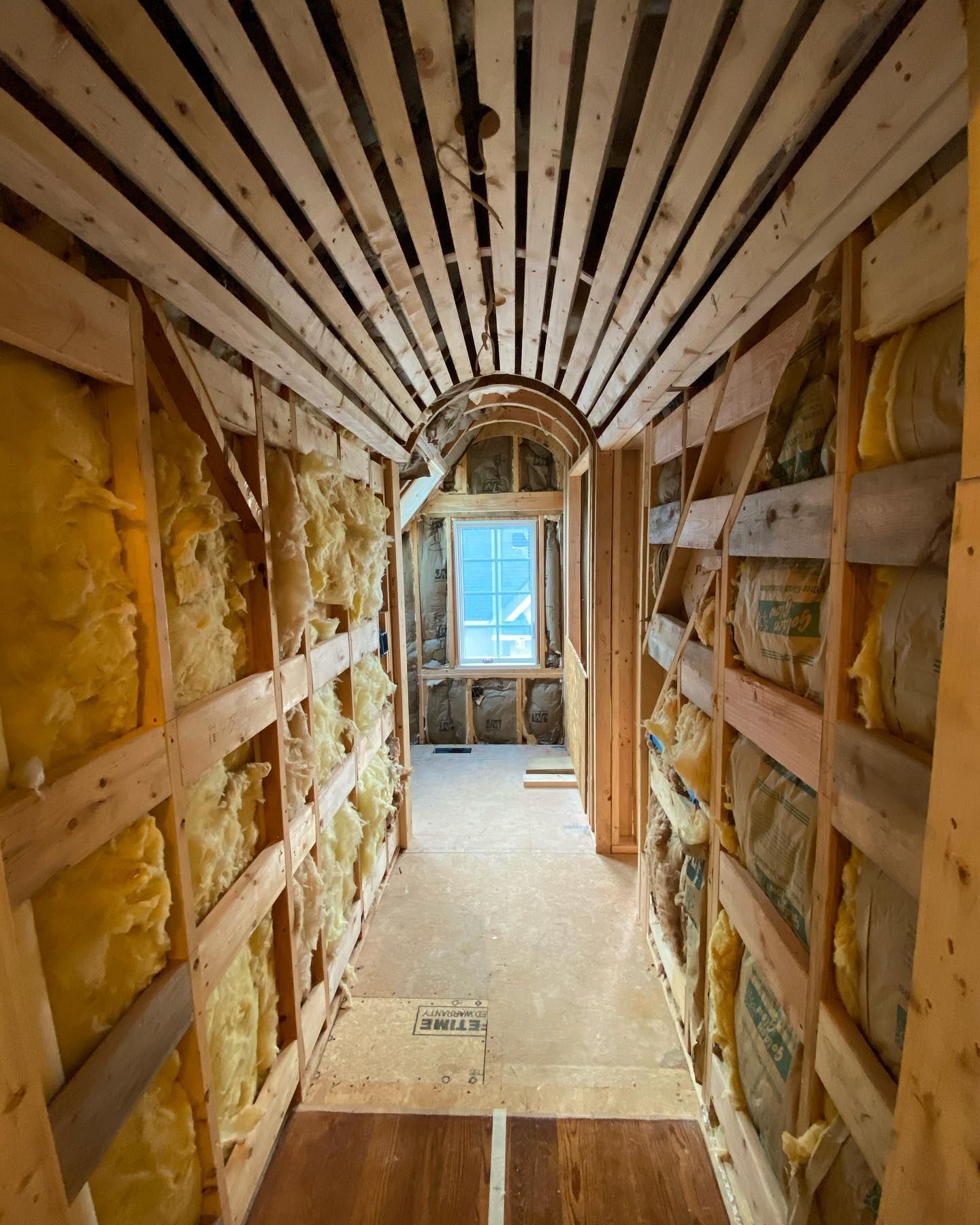 A hallway with a wooden ceiling and walls covered in insulation