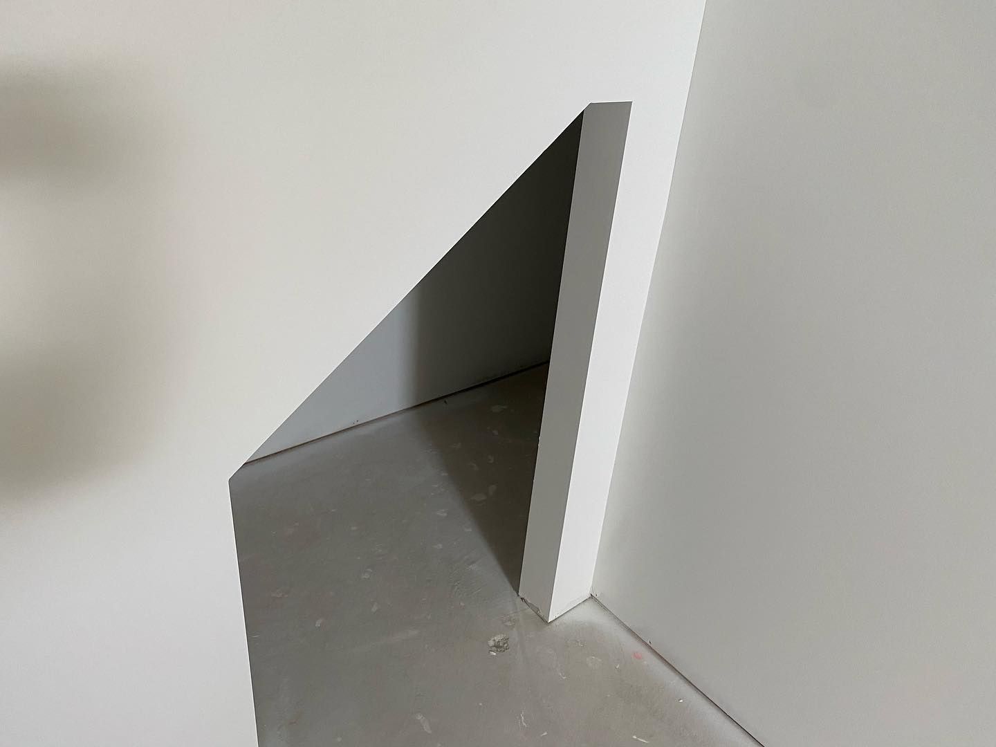 A corner of a white wall with a hole in it