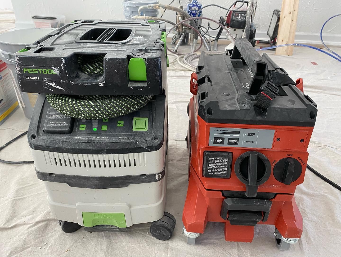 Two vacuum cleaners are sitting next to each other on a table.