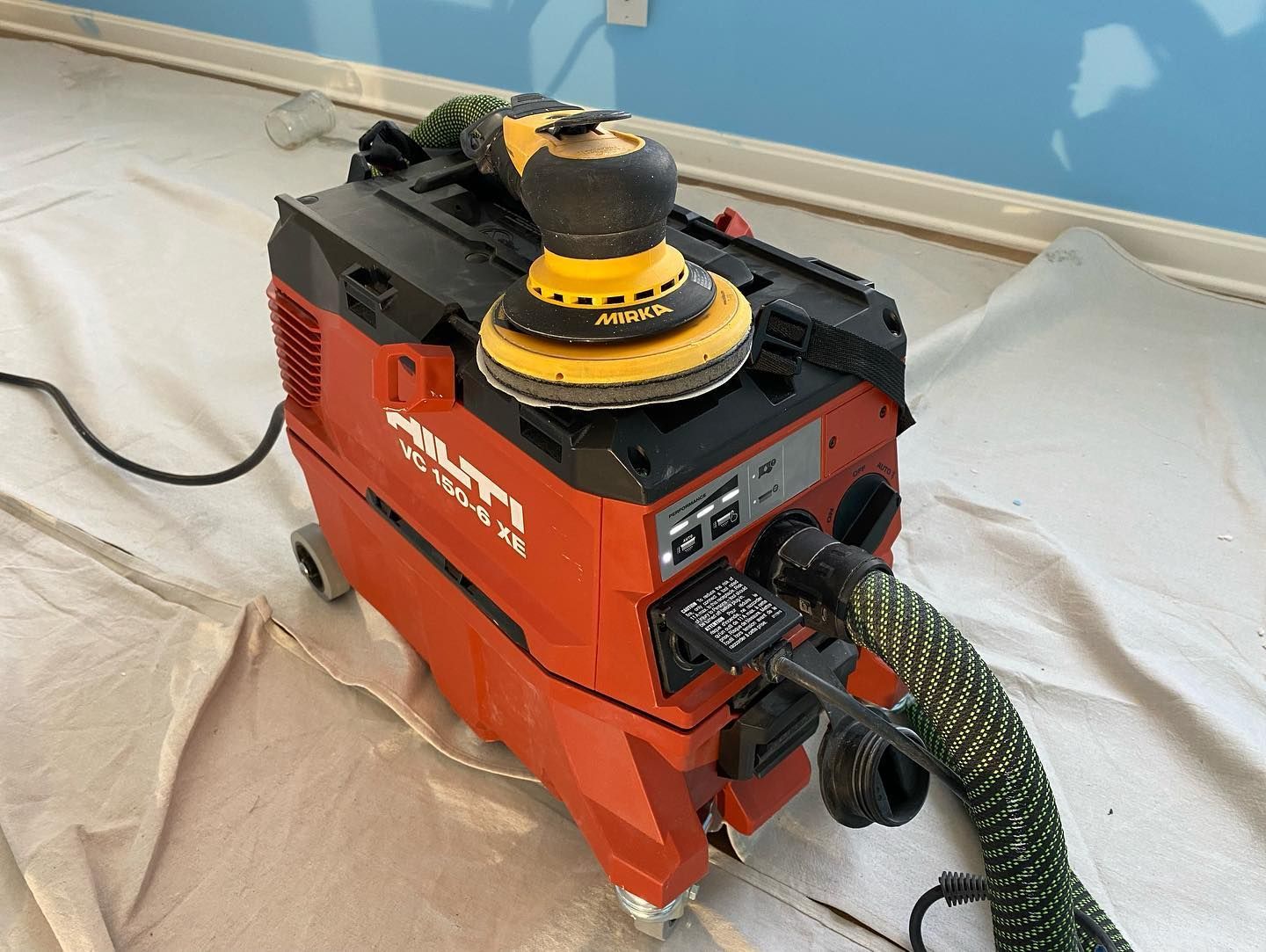 A red vacuum cleaner with a yellow sander on top of it.