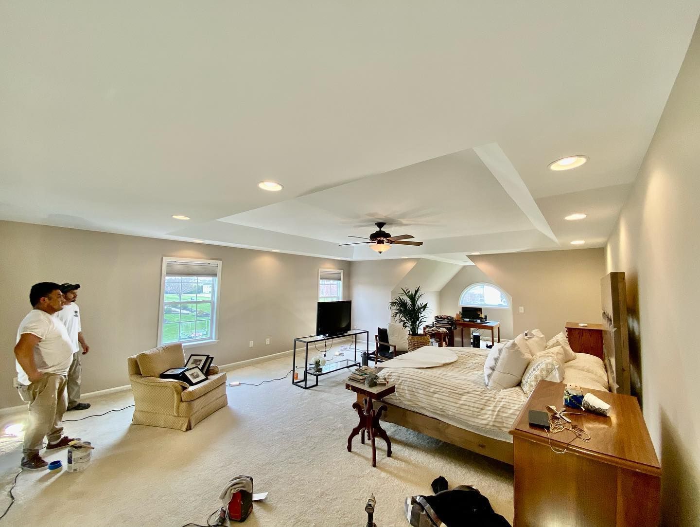 A large bedroom with a ceiling fan and a large bed.