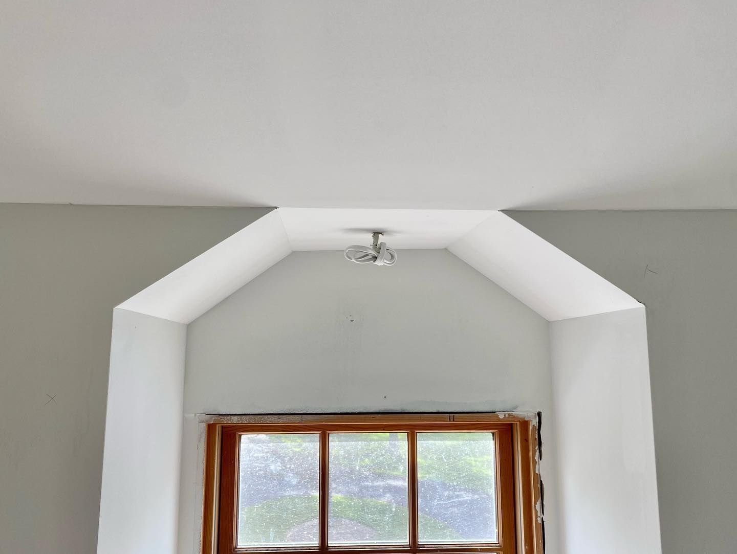 An empty room with a window and a white ceiling.