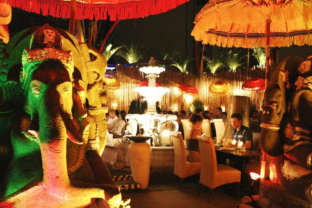 Menschen sitzen nachts an Tischen unter Sonnenschirmen in einem Restaurant