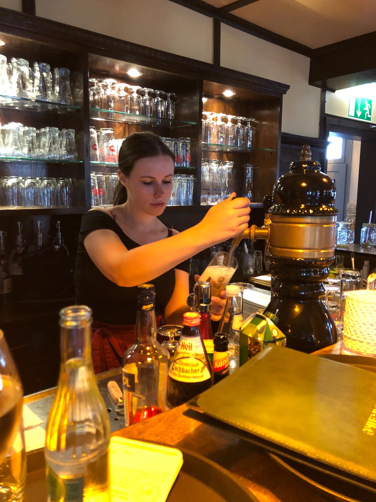 Eine Frau schenkt in einer Bar ein Getränk aus einem Zapfhahn ein