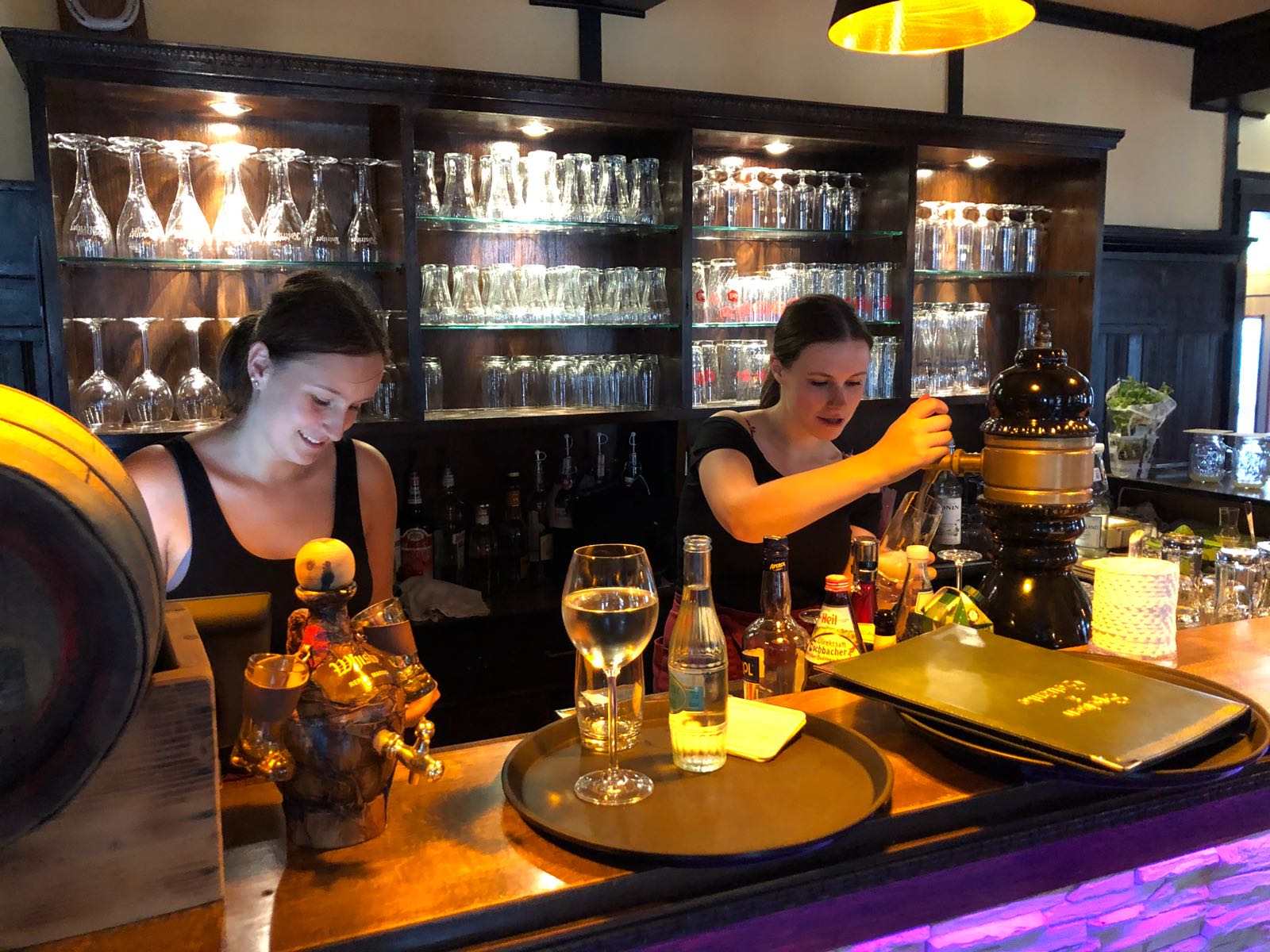 Zwei Frauen stehen hinter einer Bar und machen Drinks.
